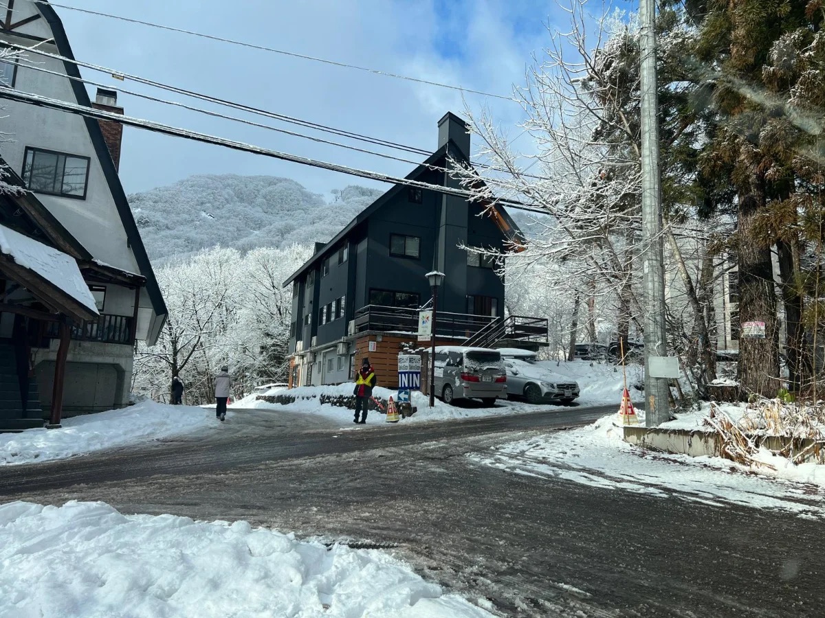 A black-clad chalet on a cleared valley road, frosted trees and a ridge behind it